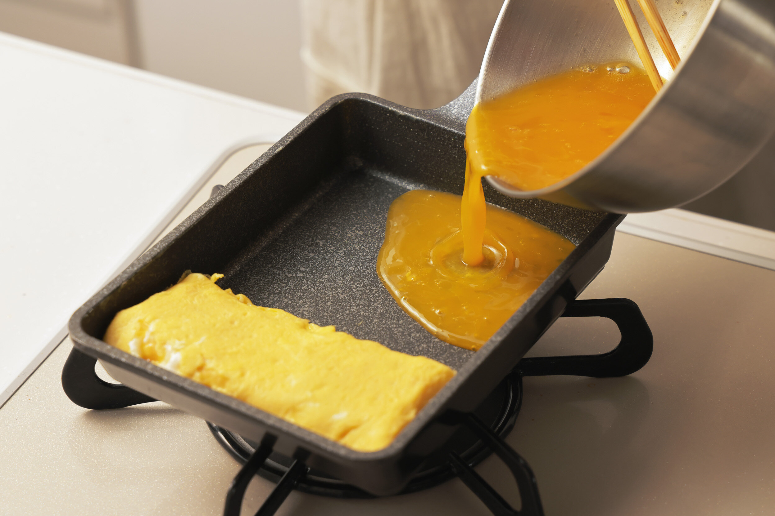 溶き卵をフライパンに流すイメージ