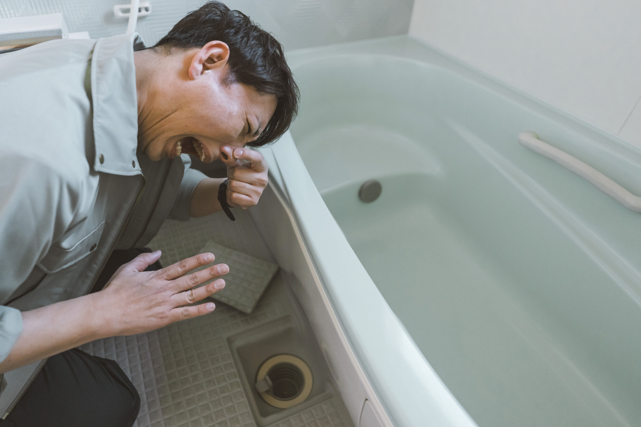 排水口の悪臭に顔をしかめる男性